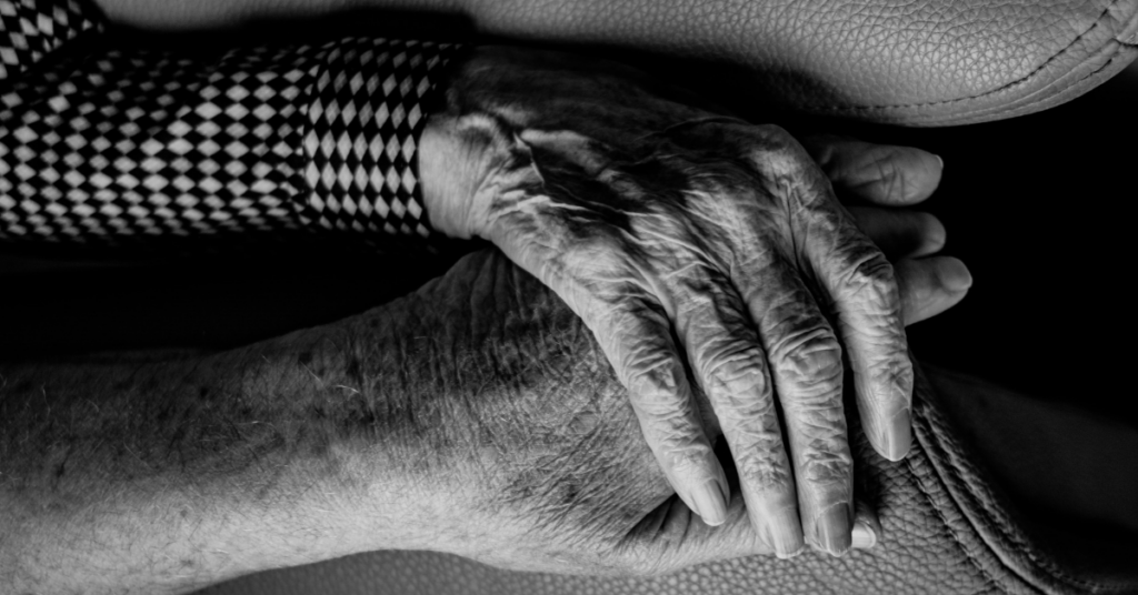 Caregiving senior couple holding hands.